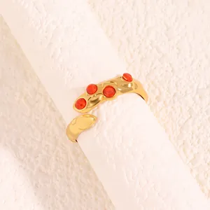 Détail d'une bague à texture de lave dorée avec quatre pierres rouges incrustées