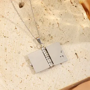 Gros plan du collier médaillon livre argenté avec découpe de cœur sur pierre texturée