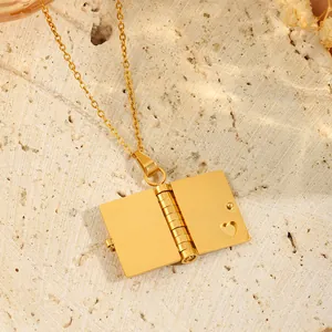 Gros plan d'un collier médaillon enveloppe dorée avec cœur évidé sur un support en pierre