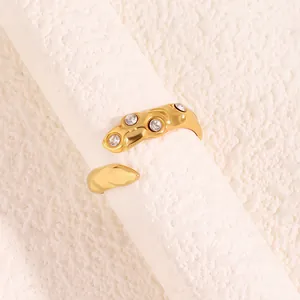 Détail d'une bague dorée irrégulière sertie de quatre zircons sur un support texturé chic