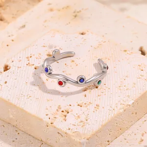 Detail of silver wavy steel ring with multicolor zircon stones on beige stone base