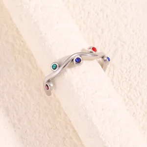 Close-up of wavy stainless steel ring with colorful inlaid stones in silver finish
