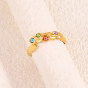 Détail d'une bague irrégulière en titane doré avec quatre zircons colorés et texture lave