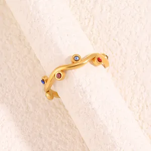 Detailed close-up of wavy gold-tone titanium ring with colorful inlaid gemstones