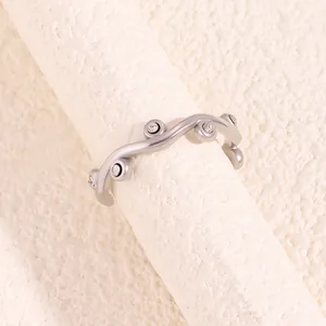 Macro shot of silver wavy titanium steel ring with sparkling crystals on textured surface