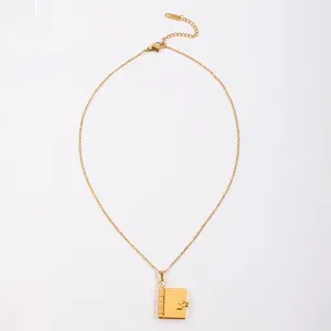 Détail du pendentif livre doré avec gravure de cœur et fermoir mousqueton ajustable