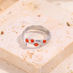 Détail d'une bague irrégulière en acier inoxydable avec pierre orange sur pierre beige