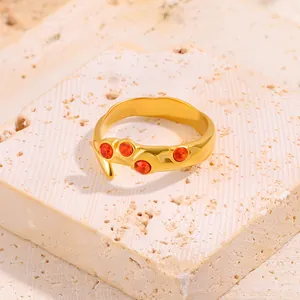 Gros plan sur la bague dorée irrégulière sertie de zircons orange sur support en pierre