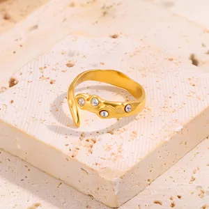 Gros plan d'une bague dorée irrégulière sertie de quatre oxydes de zirconium ronds