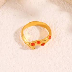 Détail de la bague dorée ondulée ornée de quatre pierres précieuses rouges en serti clos