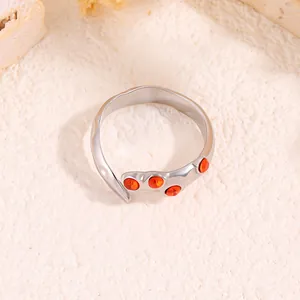 Détail d'une bague griffes argentée avec pierres orange sur pierre naturelle