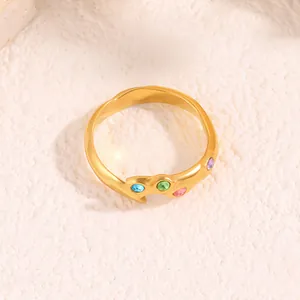 Détail d'une bague dorée ondulée en acier titane avec des zircons multicolores