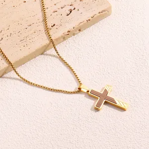 Dettaglio della collana a croce in acciaio titanio dorato con intarsio in legno scuro