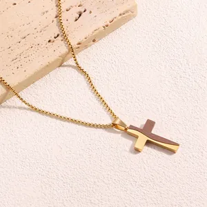 Dettaglio di un ciondolo a croce bicolore in metallo dorato lucido con inserti in legno