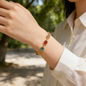 Detalle de pulsera boho dorada con piedras preciosas ovales en la muñeca de una mujer