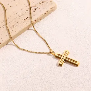 Dettaglio del ciondolo a croce in oro e acciaio con inserto in legno su catena a scatola