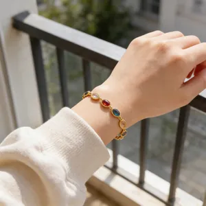 Detalle de la pulsera bohemia dorada con gemas ovaladas de colores en la muñeca de una modelo