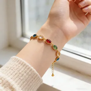 Detalle de pulsera con gemas de colores ovaladas, extensión dorada y colgante de gota