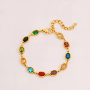 Detalle de pulsera dorada con piedras preciosas ovales de colores y bordes milgrain