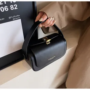 Detail of black leather handbag featuring a golden tassel clasp and flap closure