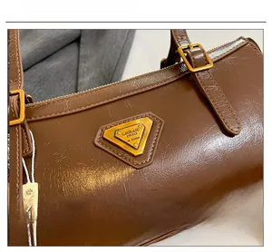 Detailaufnahme der dunkelbraunen Ölwachsleder-Textur und goldener Metallplakette
