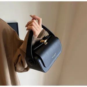 Detail of black structured leather bag with golden shell clasp and fashion text logo