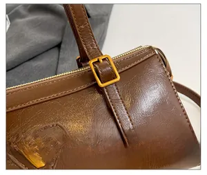 Detailaufnahme der braunen Zylindertasche aus Öl-Wachs-Leder mit goldenen Beschlägen