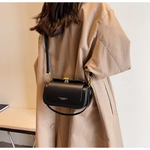 Detail of black matte leather crossbody bag with gold logo on khaki coat styling