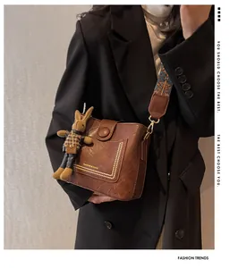 Sac seau vintage marron avec bandoulière brodée et breloque lapin porté par un mannequin