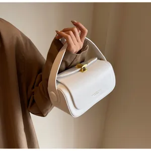 Detail of white leather handbag featuring golden fan-shaped buckle and embossed fashion text