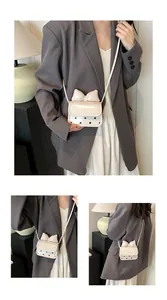 Détail d'un mini sac bandoulière avec nœud crème, rabat à pois et texte embossé