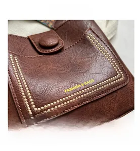 Détail d'un sac seau en cuir marron avec surpiqûres décoratives en U et bandoulière tissée