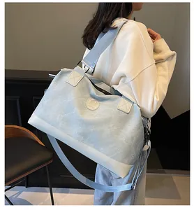 Détail du sac de voyage bleu clair avec coutures blanches et bandoulière réglable