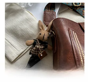Détail d'un charm lapin tricoté sur un sac en cuir marron avec chaîne dorée élégante