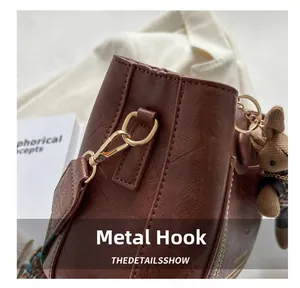 Détail du crochet doré et du sac seau marron avec charme de lapin en tricot