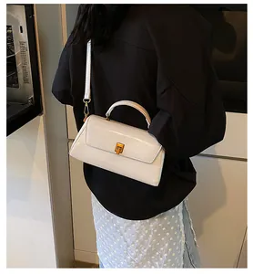 Close-up of white rectangular handbag with gold metal clasp and glossy leather texture