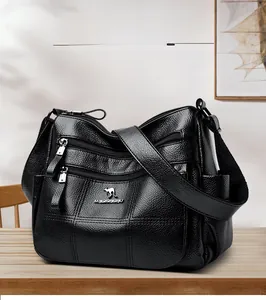 Detail of black lychee grain leather crossbody bag with multiple front zipper pockets