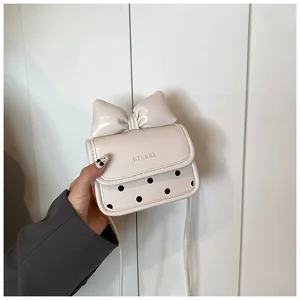 Détail du mini sac crème à bandoulière avec grand nœud et motif à pois noirs