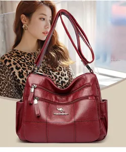 Detail view of burgundy lychee grain leather crossbody bag with multiple zip pockets