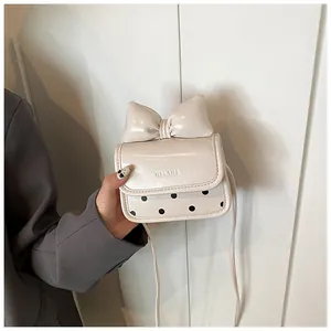 Détail du mini sac bandoulière crème avec nœud 3D et motif à pois noirs élégants