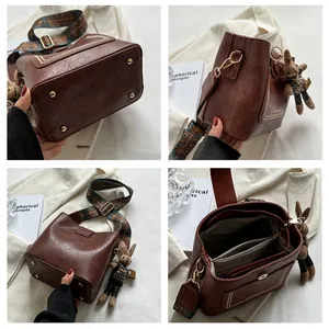 Détails du sac seau marron avec bandoulière tissée, breloque lapin et pieds de sac