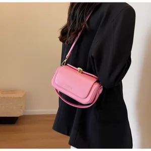 Detail of pink matte leather crossbody bag featuring gold buckle and fine shoulder strap