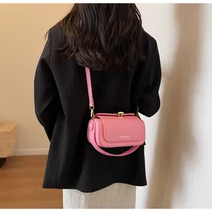 Street style view of a pink leather crossbody bag with gold buckle on a black blazer