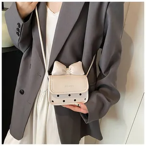 Détail du mini sac bandoulière crème avec un grand nœud et motif à pois noirs