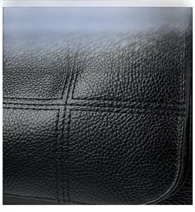 Close-up of litchi pattern leather with cross stitching and metal logo on shoulder bag
