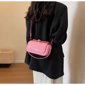 Detail of pink leather crossbody bag with gold hardware worn on a black blazer