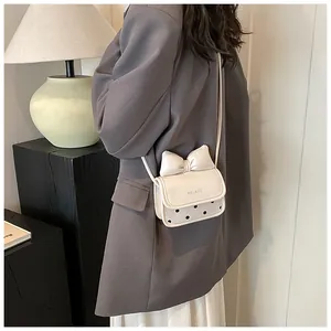 Gros plan du mini sac à bandoulière en cuir blanc avec nœud et motif à pois noirs