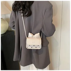 Mini sac bandoulière beige chic avec nœud 3D et pois noirs sur un blazer gris foncé