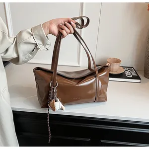 Close-up of brown glossy oil-wax leather tote bag with unique baseball sports charm