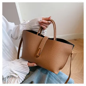 Detailed macro of brown litchi grain leather texture and metallic buckle on tote bag